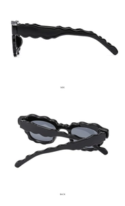 Detail view of black wavy edge sunglasses showing the unique side and back frame design