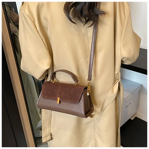 Detail of vintage brown suede leather handbag with gold metal lock and shoulder strap