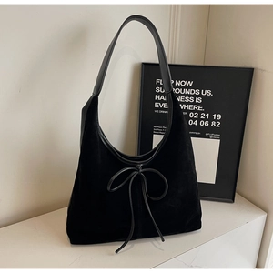 Detail of black suede hobo bag with leather strap and decorative front bow knot