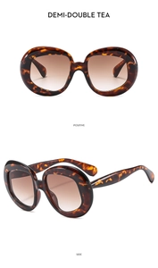 Detail view of oval tortoise shell sunglasses with gradient brown lenses and metal hinges