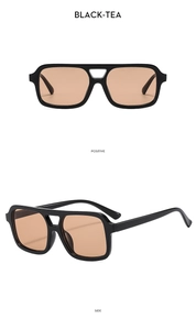 Detail of square double-bridge sunglasses with black frames and tea-tinted lenses