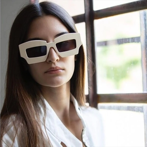 Lunettes de soleil géométriques oversize avec monture crème et verres noirs sur modèle