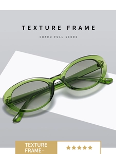 Detail view of oval emerald green translucent sunglasses frame with grey lenses