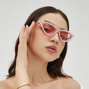 Lunettes de soleil œil de chat ornées de perles et verres roses portées par un modèle