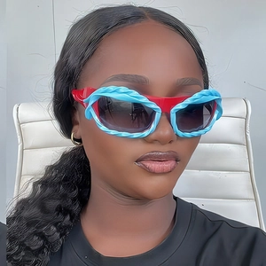 Detail of Y2K sunglasses with red frame and blue twisted trim worn by a model