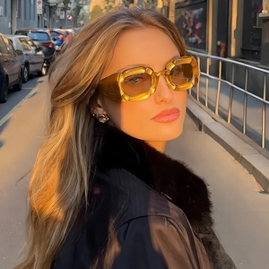 Modern irregular petal sunglasses in amber translucent frame worn by a model in sunlight