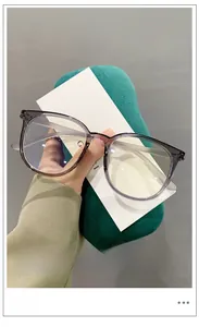 Detail of transparent grey-purple TR90 glasses frame held against a green velvet pouch