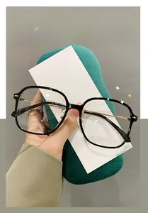 Detail of square black frame glasses with thin gold metal temples and clear blue light lenses