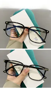 Detail of glossy black TR90 frames with golden cross accents and anti-blue light lenses