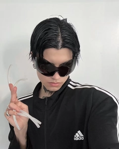 Detail of Y2K futuristic wrap sunglasses paired with black sporty three-stripe jacket