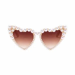 Detailed view of white pearls on heart-shaped frame and gradient brown lenses