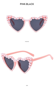 Detail of pink heart sunglasses with pearl embellishments and dark lenses shown from two angles