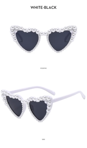 Detail of heart-shaped sunglasses with pearl-encrusted white frames and dark lenses