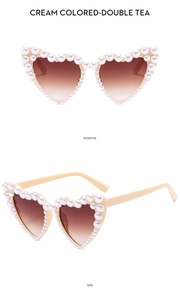 Detail of cream heart-shaped sunglasses with pearl trim and brown gradient lenses