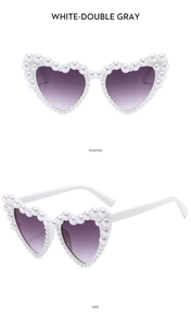 Detail view of heart-shaped white sunglasses with pearl accents and purple gradient lenses
