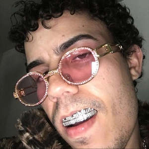Hip-hop oval sunglasses with gold diamond-encrusted frames and pink lenses shown on model
