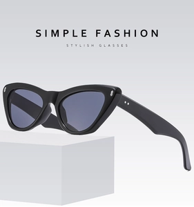 Detail of black cat-eye glasses frame with metallic studs on white geometric stand