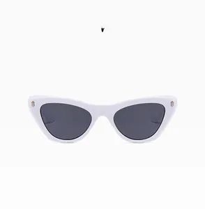 Close-up of retro cat-eye white frame glasses with dark grey lenses and gold studs
