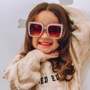 Kleinkind trägt quadratische Glitzer-Sonnenbrille mit Perlenrahmen und braunen Gläsern