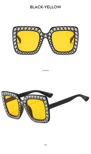 Detailansicht der quadratischen schwarzen Sonnenbrille mit gelben Gläsern und Strass