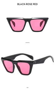 Detail view of black oversized sunglasses with rose red lenses and metal stud accents