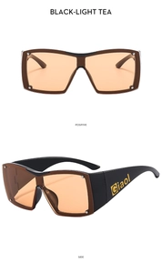 Detail of square Y2K sunglasses with black frame, orange lenses and silver metal rivets