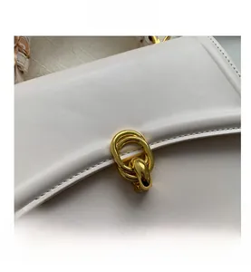 Detail of white leather handbag featuring gold triple-ring clasp and silk scarf handle