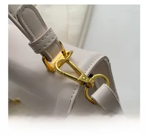 Close-up of golden metal buckle and swivel hook on minimalist beige crossbody bag