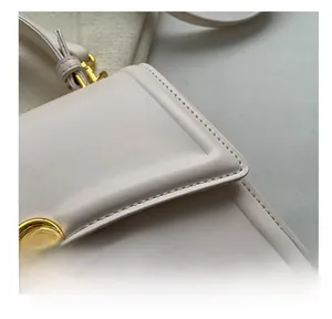 Close-up of precise stitching and gold chain detail on beige leather handbag