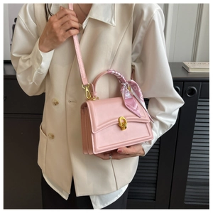 Pink square handbag featuring a patterned silk scarf handle and golden metal lock