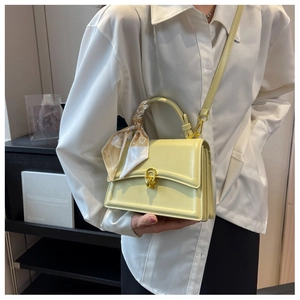 Close-up of yellow square shoulder bag with silk scarf handle and gold ring buckle detail