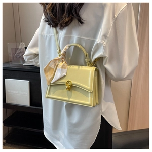Detailed view of yellow crossbody bag with silk scarf handle and golden horsebit clasp