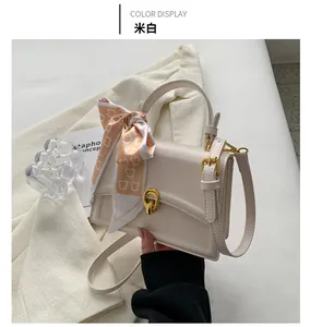 Detail of cream square leather bag with gold twist lock and printed silk scarf handle