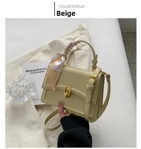 Detail view of yellow leather crossbody bag with silk scarf handle and gold lock