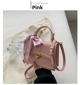 Detailed shot of pink square bag with golden twist lock and heart print silk scarf handle