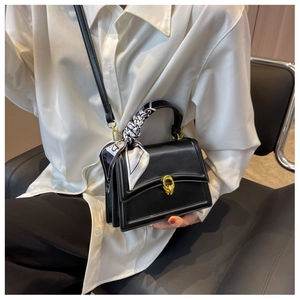 Chic black square bag with golden twist lock and silk scarf detail shown on model