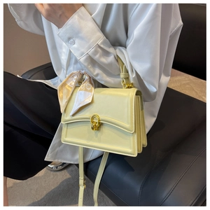 Detail of light yellow square bag with golden horseshoe clasp and printed silk scarf