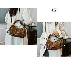 Macro view of brown pleated oil wax leather cloud bag with glossy texture and gold metal accents