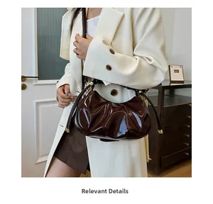 Detail of dark brown pleated oil-wax leather texture and gold adjustable shoulder strap