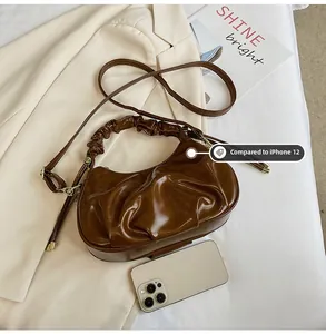 Caramel oil-wax leather dumpling bag size comparison with an iPhone 12 for reference