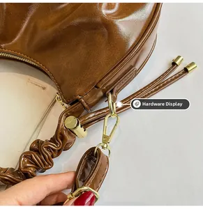 Close-up of caramel leather bag with golden hardware and pleated strap details