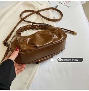 Detailed bottom view of brown pleated faux leather cloud bag with smooth finish