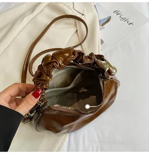 Detail shot of the brown pleated handbag interior with golden zipper and compartments