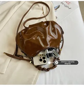 Detail showing internal capacity of brown pleated dumpling bag with phone and cosmetics