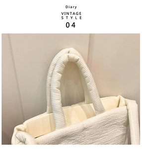 Close-up of quilted tote bag handle, soft padded fabric texture, minimal style detail view.