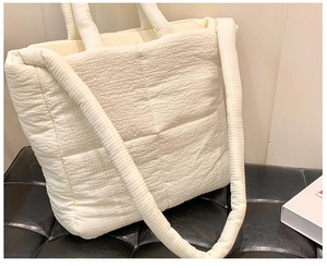 Detail view of the quilted puffer tote bag in off-white, featuring soft padded texture and strap.