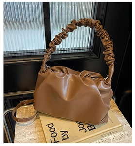 Detail of a brown ruched cloud bag showing soft PU leather texture and gold metal hardware