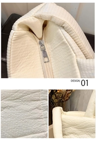 Close up detail of quilted tote bag zipper hardware and soft padded fabric texture.