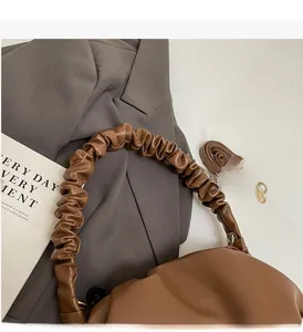Detail of caramel pleated cloud bag featuring soft handle and smooth leather texture