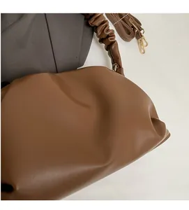 Detailed macro view of the soft caramel brown pleated fabric and golden metal strap buckle